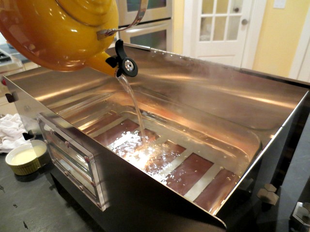 Pouring hot water into a 9x13 pan in HERC Oven